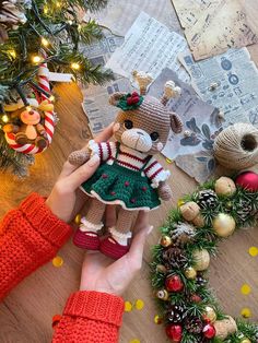 someone is holding a stuffed animal in front of christmas decorations and garlands on the table