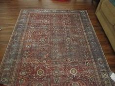 an old rug is laying on the floor in front of a couch and coffee table