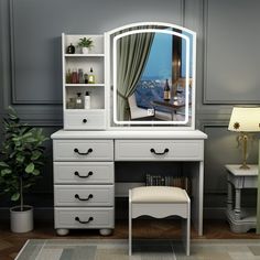 a white dressing table with a mirror and stool next to a potted green plant