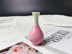 a pink vase sitting on top of an open book