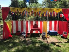 an outdoor party with red, yellow and white striped curtains on the side of it