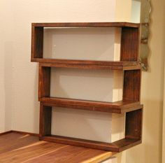 a wooden shelf sitting on top of a hard wood floor next to a white wall