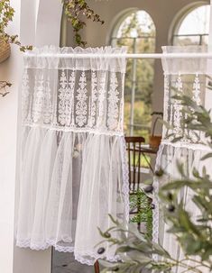 the sheer curtains are hanging from the outside of the house with plants growing on it