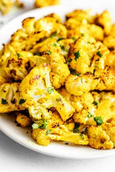 a white plate topped with cooked cauliflower on top of a table