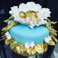 a blue and gold cake with white flowers on it