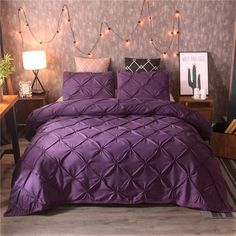 a bed with purple comforter and pillows in a room decorated with string lights on the wall