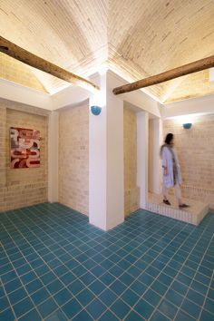 a person walking in an empty room with blue tiles on the floor and white walls