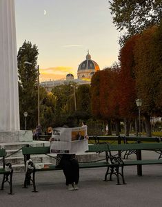 people are sitting on benches in front of a monument and looking at the papers they're reading