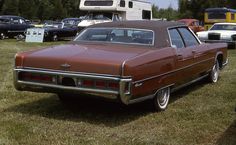 an old car is parked in the grass near other cars and rvs on display