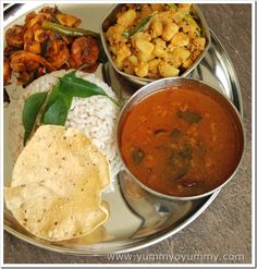 a silver plate topped with different types of food next to rice and sauces on a table