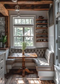 a room with a couch, table and shelves in it's corner area next to a window