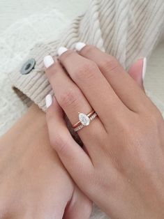 a woman's hand with a diamond ring on her left hand and a white sweater