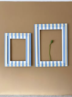 two blue and white striped frames with a single flower in the middle on a tan wall