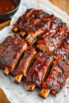 ribs covered in bbq sauce sitting on top of parchment paper