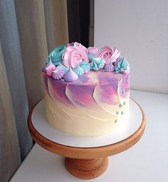 there is a cake that has flowers on the top and bottom of it, sitting on a wooden stand