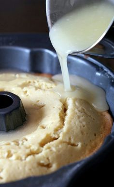 someone pouring batter on top of a cake in a pan