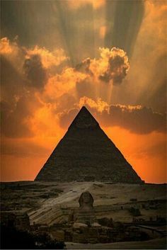 the sun is setting over the great pyramid in giza, with rays coming through the clouds