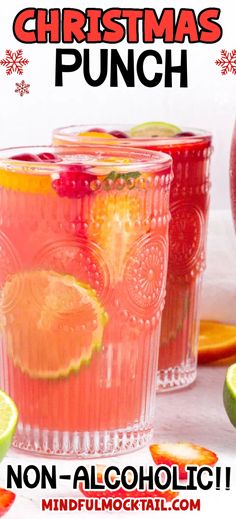 two glasses filled with christmas punch next to sliced oranges and lime slices on the table