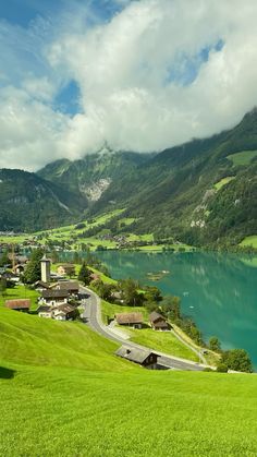 a scenic view of a lake surrounded by lush green hills and mountains in the distance