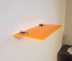 an orange shelf is hanging on the wall