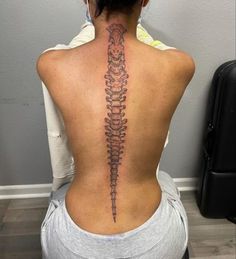 the back of a woman's neck with a skeleton tattoo on her lower back