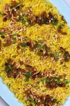 a white plate topped with yellow rice and nuts