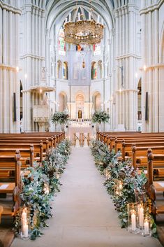 an empty church filled with wooden pews covered in greenery and lit by candles