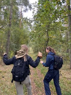 two people standing in the woods holding hands