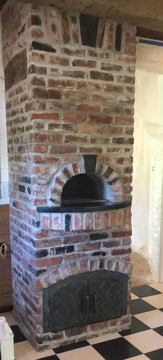 an outdoor brick oven in the middle of a checkerboard floored kitchen area