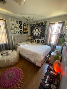 a bedroom with a bed, rugs and pictures on the wall above it in front of two windows