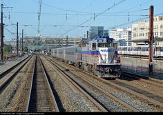 a train traveling down tracks next to tall buildings and power lines in the city area