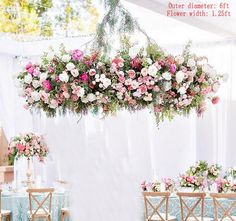 an arrangement of pink and white flowers hanging from a chandelier over a banquet table