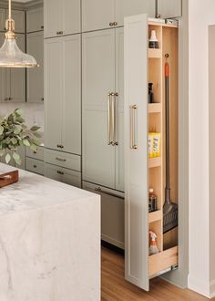 an open cabinet in the middle of a kitchen with marble counter tops and wooden flooring