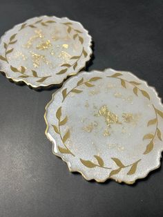 two white and gold plates sitting next to each other on a black counter top,