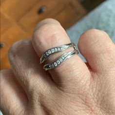 a person's hand with two silver rings on top of their fingers and one is holding