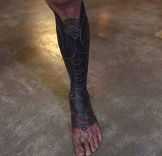 a man's leg with tattoos on it is standing in the middle of the floor