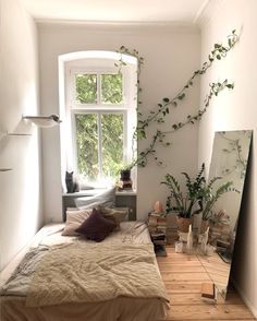 a bed room with a neatly made bed next to a window and a mirror on the wall