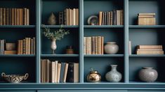 a blue bookcase filled with lots of books and vases on top of it