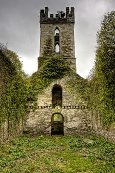 an old stone building with ivy growing on it's sides and a bell tower in the background