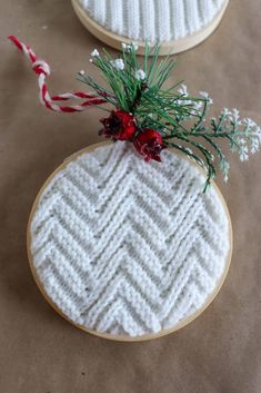 two christmas ornaments made out of yarn and wood are sitting on a table next to each other