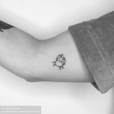 a black and white photo of a crab tattoo on the left inner arm, which has a small fish in it's center