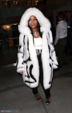 a woman wearing a white and black fur coat