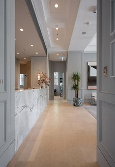 an empty lobby with marble counter tops and white walls, along with potted plants