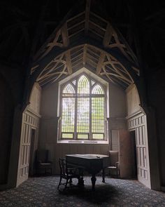 an empty room with a table and chairs in front of a large stained glass window