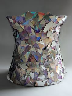 an unusual vase made out of small pieces of iridescent material is shown in this image