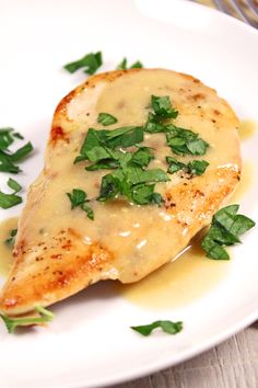 a white plate topped with chicken covered in gravy and garnished with parsley