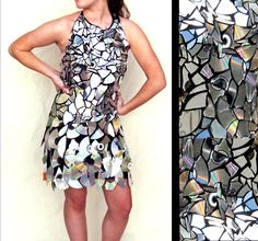 a woman standing in front of a wall and wearing a dress made out of cds