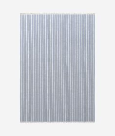 a blue and white striped rug with fringes on the bottom, in front of a gray background