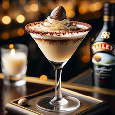 a chocolate dessert in a martini glass on a table next to a bottle of booze