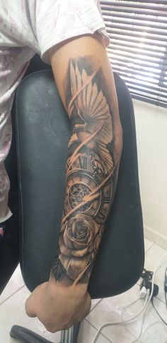 a person sitting in a chair with a tattoo on their arm and the clock behind them